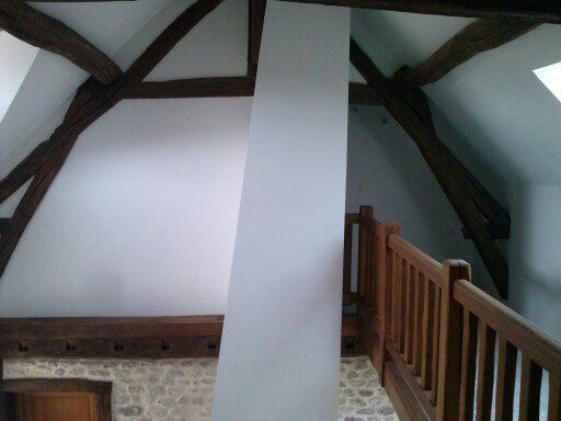Intérieur rénové par Michel VAZ : mezzanine en bois, mur de pierre et peinture claire